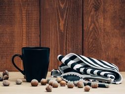 black mug, striped napkin and uncracked hazelnuts