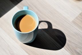 a blue mug of cuppucino in the morning