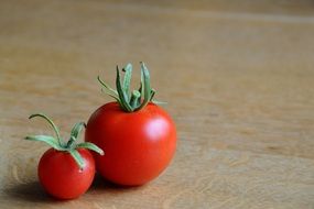 small and big fresh tomatoes on a wooden counter