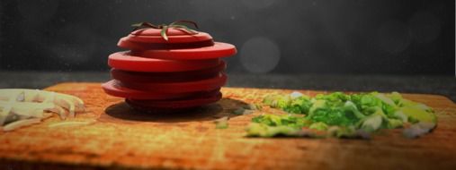 sliced up tomatoe on a wooden board with other vegetables