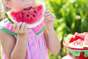 young girl eating watermelon in the summer