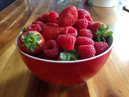 red bowl completely filled with strawberries and raspberries