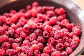 fresh bright raspberries in a wooden bowl