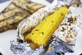 cob of grilled corn in shiny foil