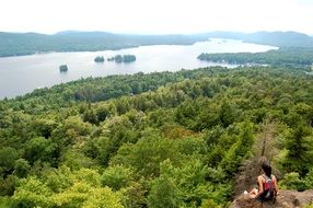 girl sits on a cliff above the trees