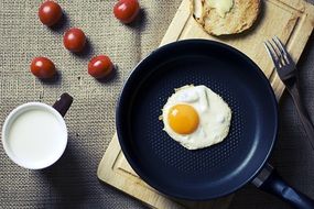 breakfast on a cutting board of tomatoes, toast, and eggs