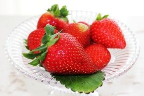 a few strawberries on a crystal plate