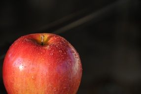 drops of water on a red apple on a black background