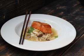 piece of salmon an noodles with cho;sticks in a restaurant