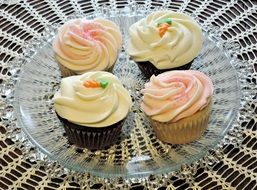 Cupcakes with different decorations on a glass plate