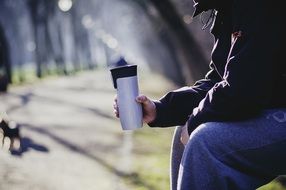 take away coffee cup in hand at park