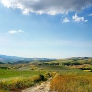 panoramic view of a sandy path among green hills