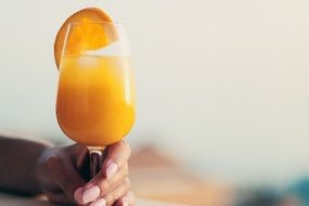 citrus drink in a glass in a man's hand