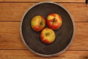 three apples in the wooden plate