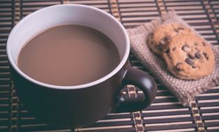 cup of coffee with chocolate chip cookies on the table