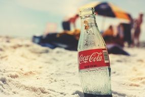 coca cola bottle in a sand