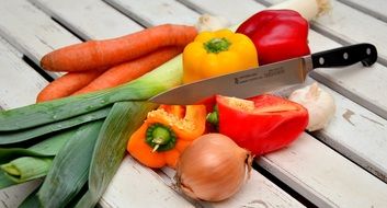 vegetables and knife lie on a wooden board