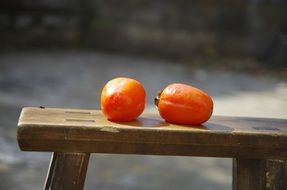 Two fruits lie on a bench