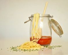 spaghetti noodles and tomato sauce in a glass jar