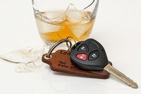 car key and cracked glass of whiskey