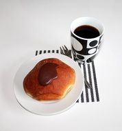 pancake on a plate near a cup with a coffee