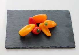 Red and orange peppers on the black board