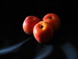 three apricots lie on a dark blue background