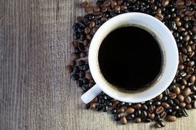 cup of coffee standing on coffee beans