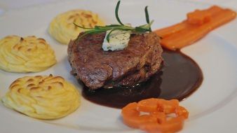 mashed potatoes and steak with sauce on a plate