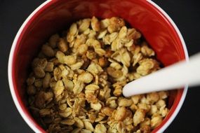 muesli with milk in a red bowl for breakfast