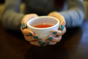 tea cup in hands with green nails