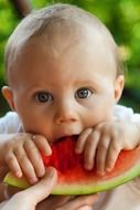 a small child is eating watermelon
