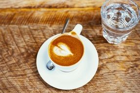 espresso coffee in cup and water in glass on wooden table