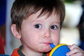 little boy with big eyes drinks from cup