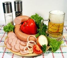 a glass of beer near the sausage plate