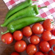 Red tomatoes and green peppers on the table with white, purple and red cloth