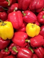 two yellow bell peppers among red ones