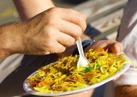 man eats pasta from plastic dishes