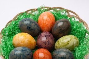 colorful easter eggs in a wicker basket on green