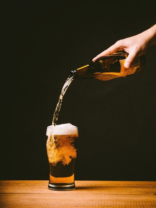 foamy beer poured in a small glass