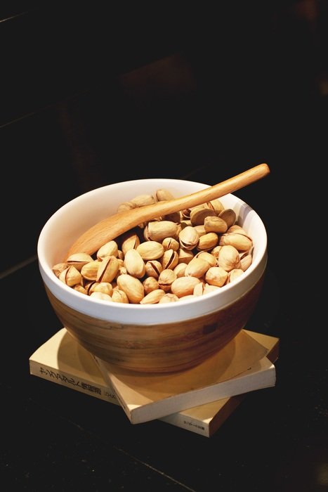 full bowl of pistachio on black glossy table