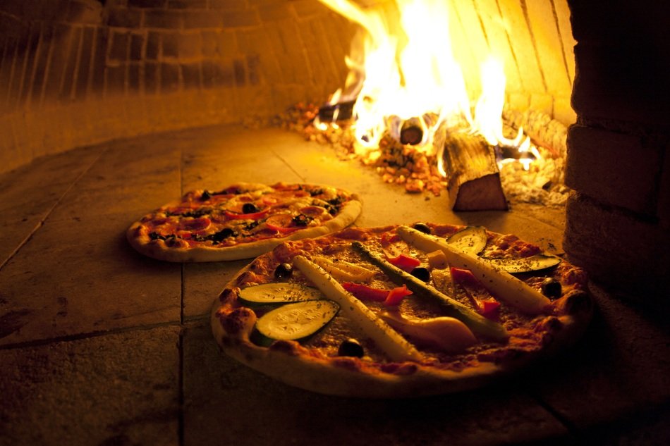 two pizzas on a background of fire in the oven