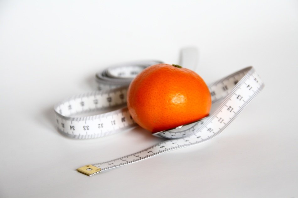Mandarin and measuring tape at light background