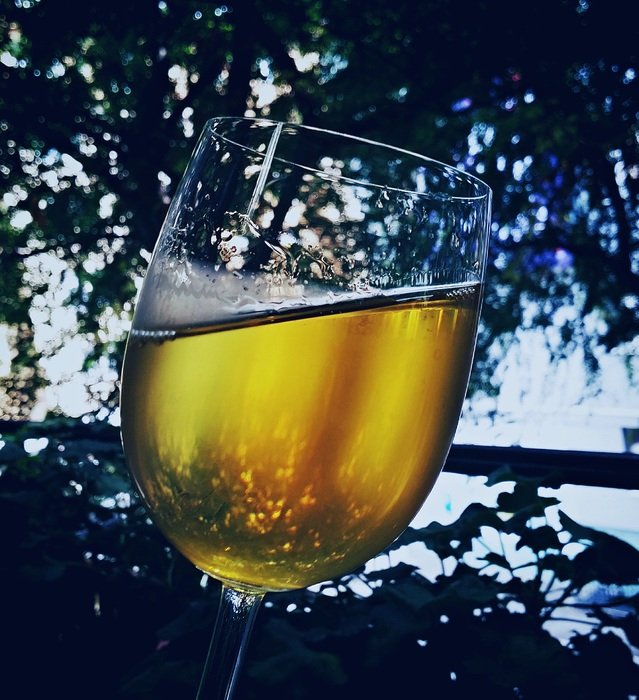 a glass of chilled wine on a background of trees
