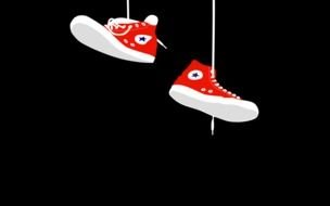 red sneakers hang on shoelaces on a black background