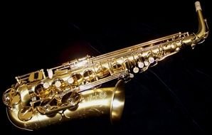 photo of golden shiny saxophone on black background