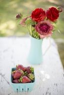 rose bouquet and strawberries in box on table