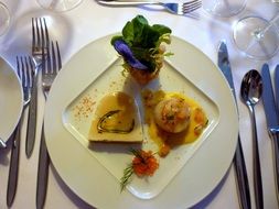 Scallop with the salad on a white plate in a restaurant