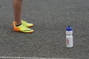 sports shoes on asphalt drink bottle