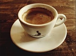 white cup with espresso coffee on wooden surface